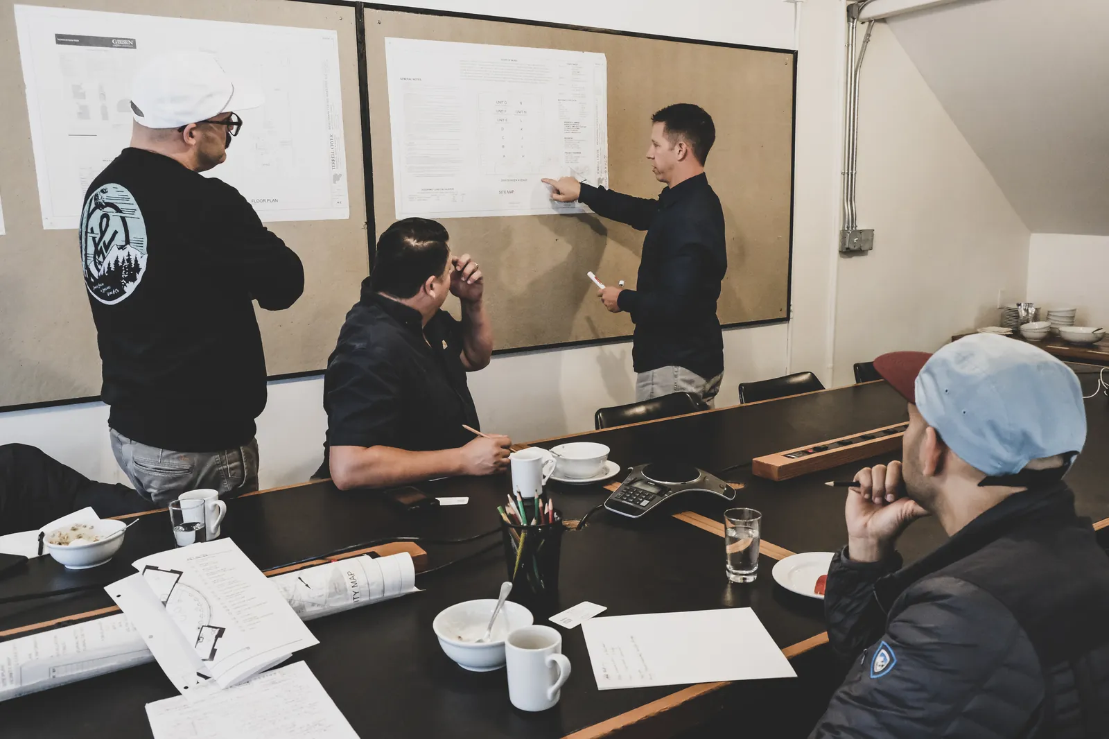 Matt Powers walking a team through a floor plan pinned to a board during a planning session